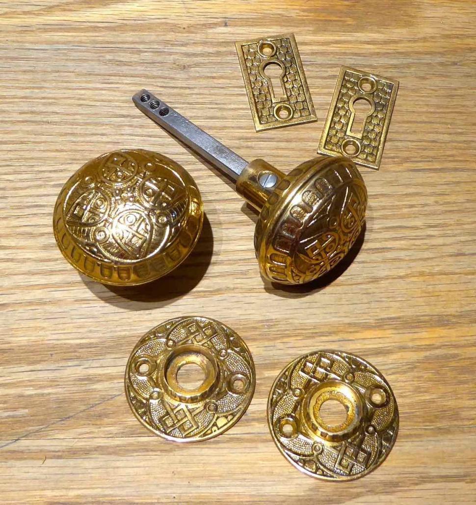 Antique brass Eastlake door hardware sets. Set includes: patterned doorknobs, patterned rosettes, patterned escutcheons.