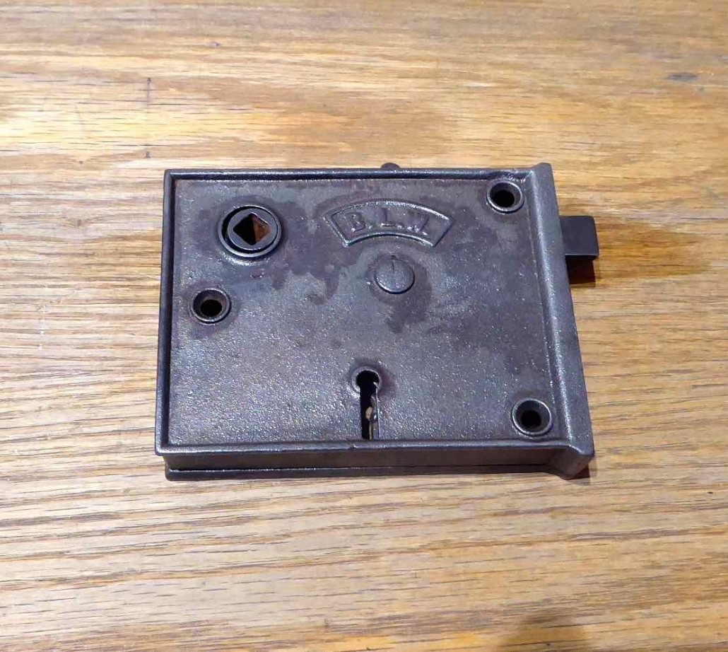 Antique Cast Iron rim lock, manufactured and signed on both sides with B.L.W. shield logo. Lock has a night latch for privacy without using the keyed deadbolt, and has reversible handing.