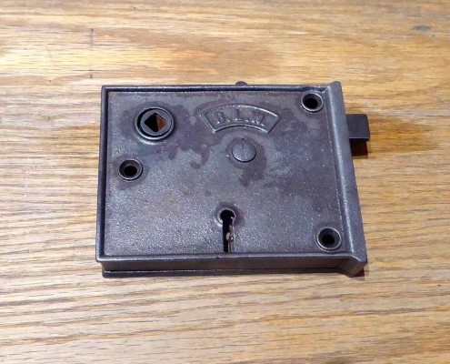 Antique Cast Iron rim lock, manufactured and signed on both sides with B.L.W. shield logo. Lock has a night latch for privacy without using the keyed deadbolt, and has reversible handing.