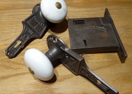 Original Victorian style cast iron passage set with porcelain door knobs and cast iron gravity lock. Gravity lock made by Gurney. Features porcelain doorknobs built into patterned backplates.