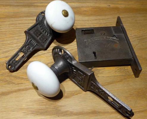 Original Victorian style cast iron passage set with porcelain door knobs and cast iron gravity lock. Gravity lock made by Gurney. Features porcelain doorknobs built into patterned backplates.