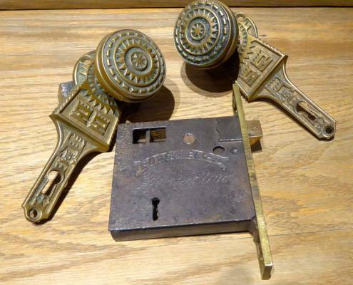 Antique Victorian style cast iron passage set with solid brass doorknobs and cast iron gravity lock. Gravity lock made by Gurney. Features solid brass doorknobs built into patterned brass backplates.